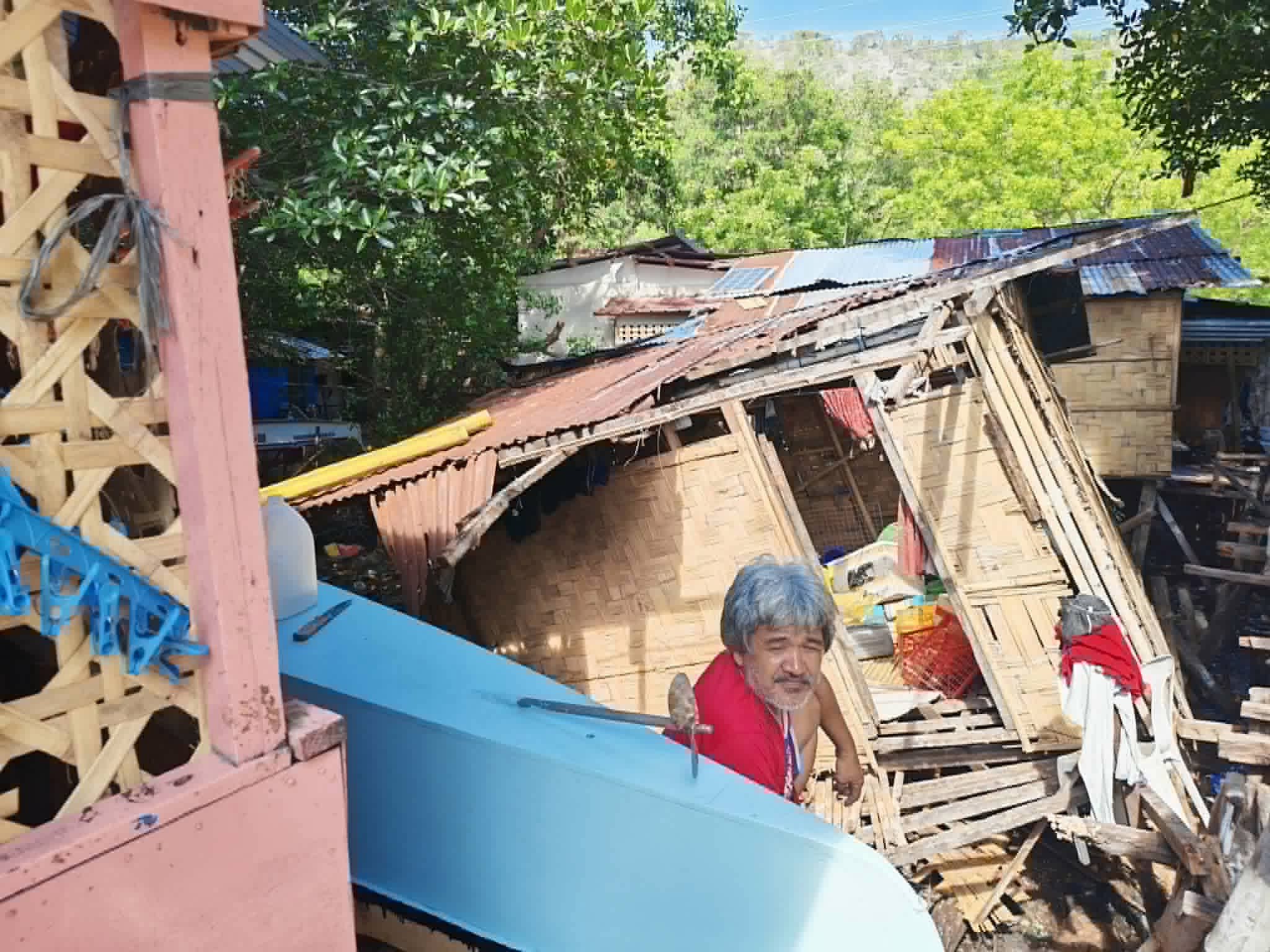 A man sits in the remains of buildings destroyed by the Mindanao earthquake in June 2026