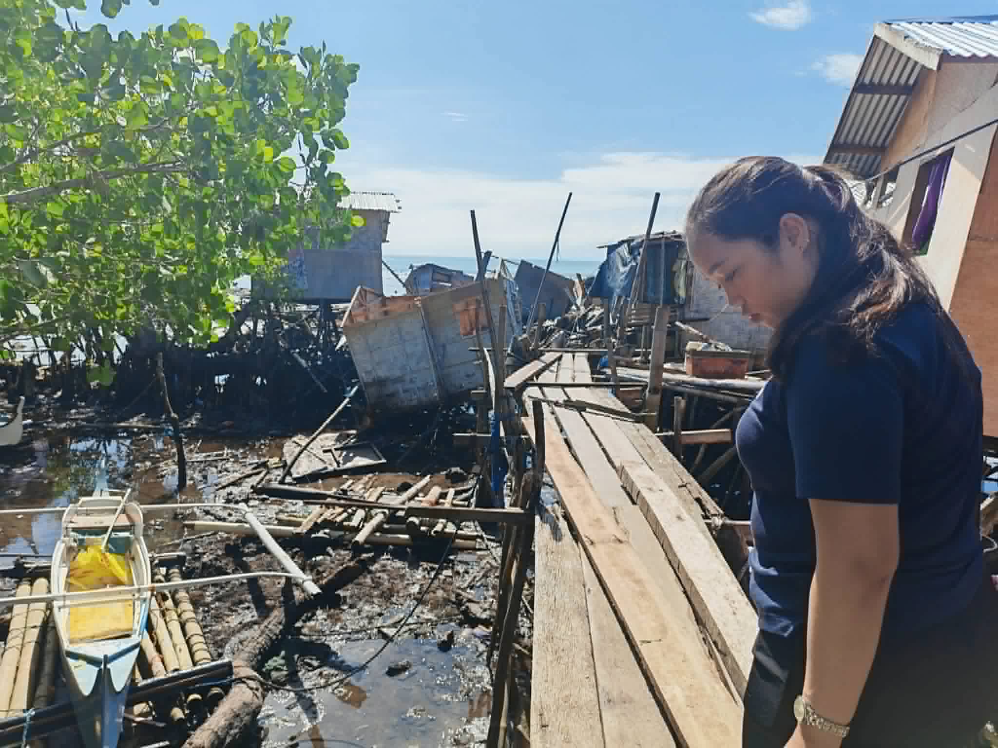 A woman stands amidst a pier and several buildings destroyed by the Mindanao earthquake in June 2026